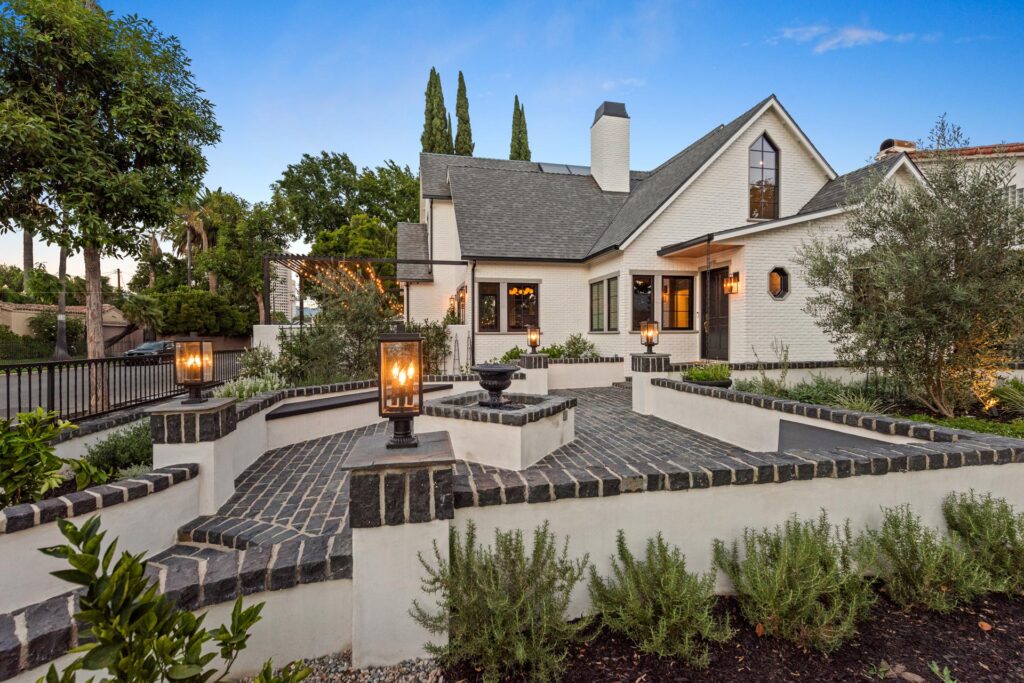 Formal front entry garden with black cobblestone and white brick walls